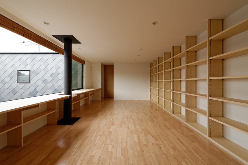 Esempio di un grande studio contemporaneo con libreria, pareti bianche, parquet chiaro, scrivania incassata e pavimento beige