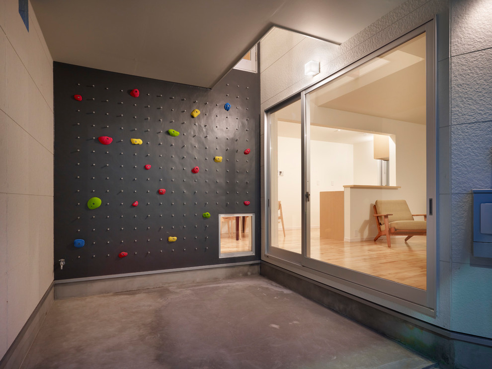 Moderner Fitnessraum mit Kletterwand, grauer Wandfarbe, Betonboden und grauem Boden in Tokio