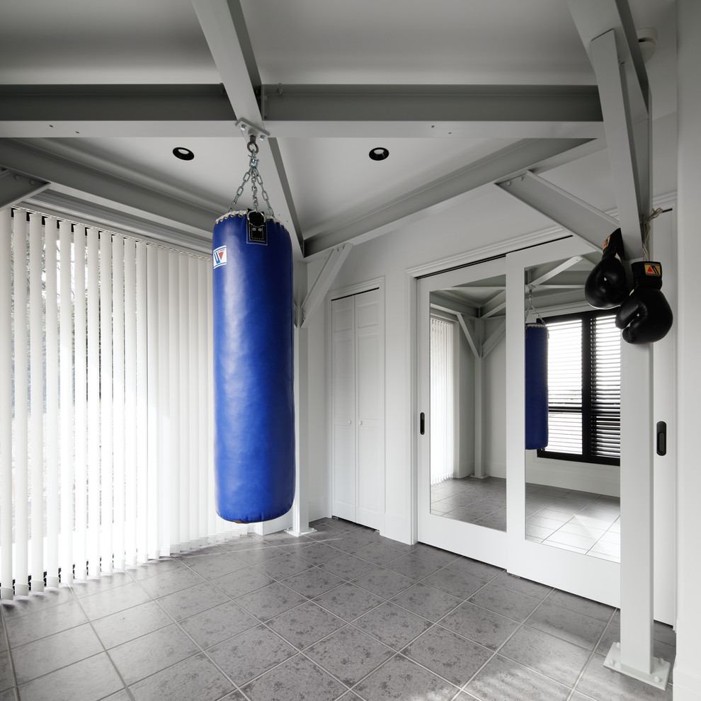 Cette image montre une salle de musculation minimaliste avec un mur blanc et un sol gris.