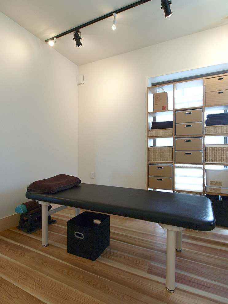Photo of a scandi home weight room in Tokyo with white walls, light hardwood flooring and beige floors.