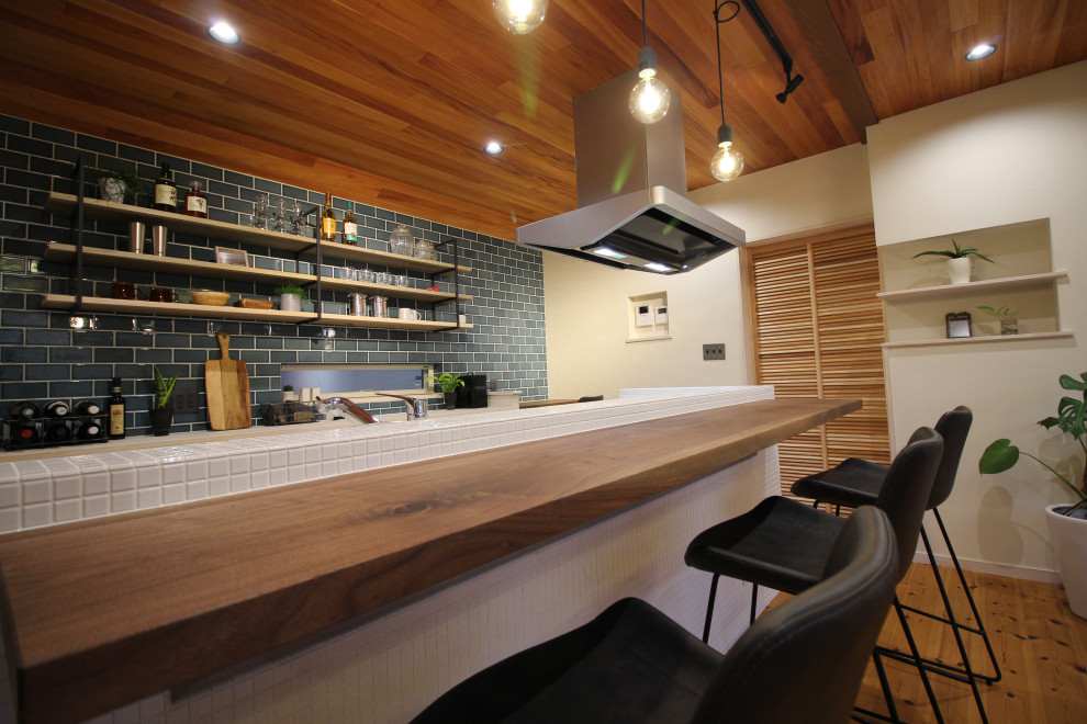 Example of a mid-sized asian single-wall medium tone wood floor and brown floor seated home bar design in Other with an integrated sink, open cabinets, white cabinets, tile countertops, blue backsplash, ceramic backsplash and brown countertops
