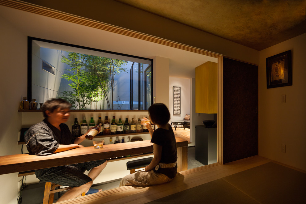 Idée de décoration pour un bar de salon minimaliste avec des tabourets et un placard sans porte.