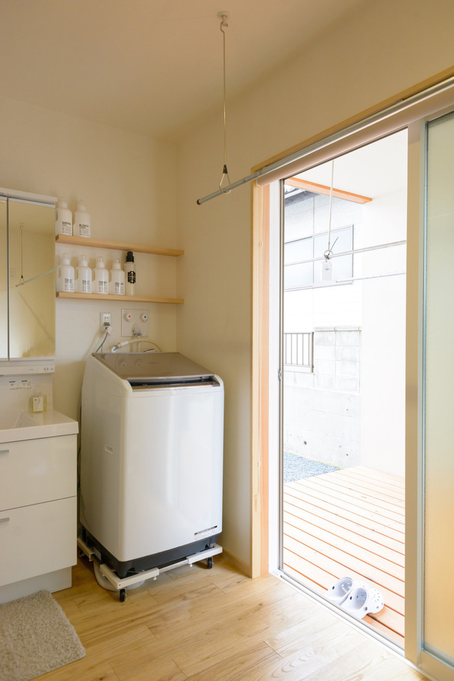 Diseño de lavadero multiusos y en L nórdico de tamaño medio con fregadero integrado, paredes blancas y suelo de madera en tonos medios