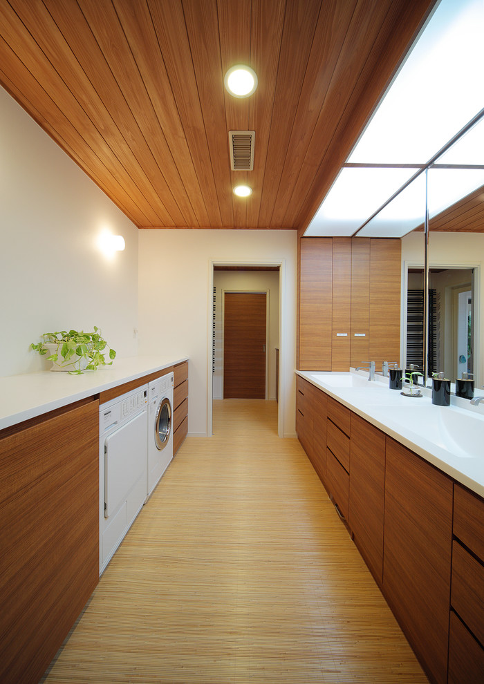 Diseño de lavadero contemporáneo con fregadero integrado, armarios con paneles lisos, puertas de armario de madera oscura, paredes blancas y suelo marrón