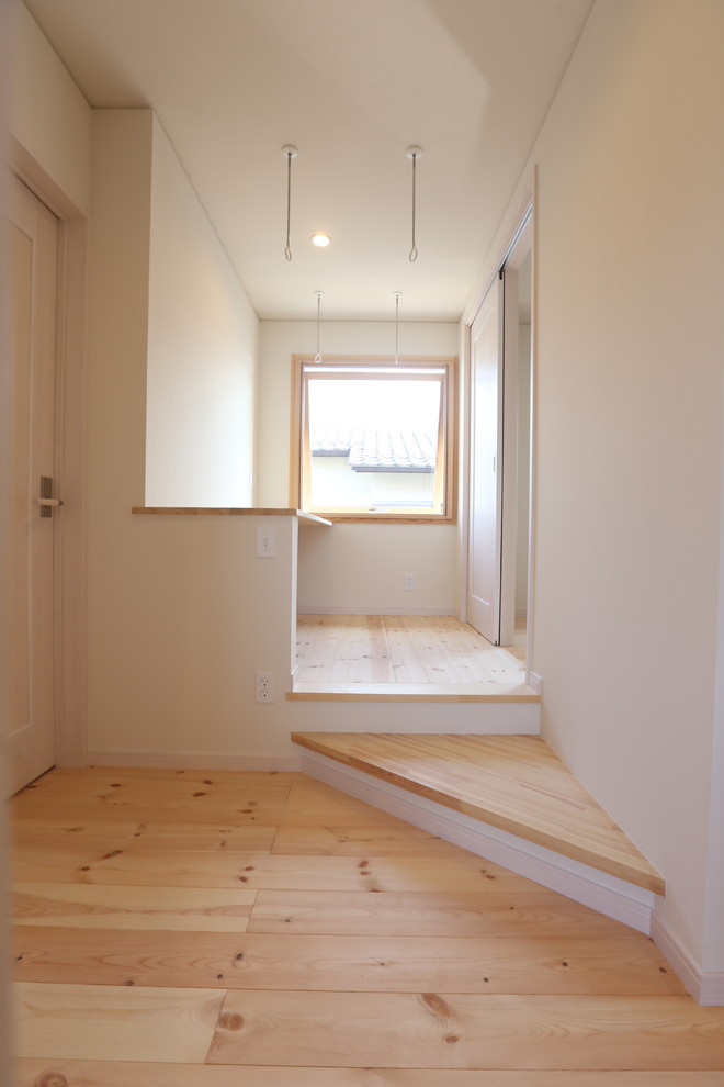 Foto di una piccola lavanderia scandinava con pareti bianche, pavimento in legno massello medio e pavimento beige