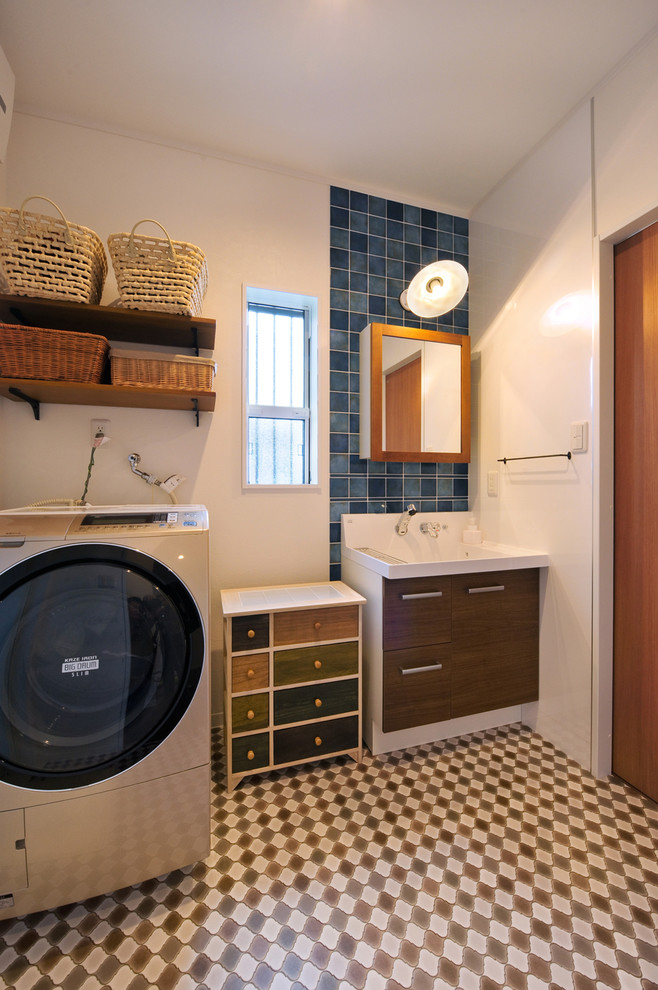 Esempio di una lavanderia etnica con ante lisce, ante in legno bruno, pareti bianche, pavimento multicolore e lavasciuga