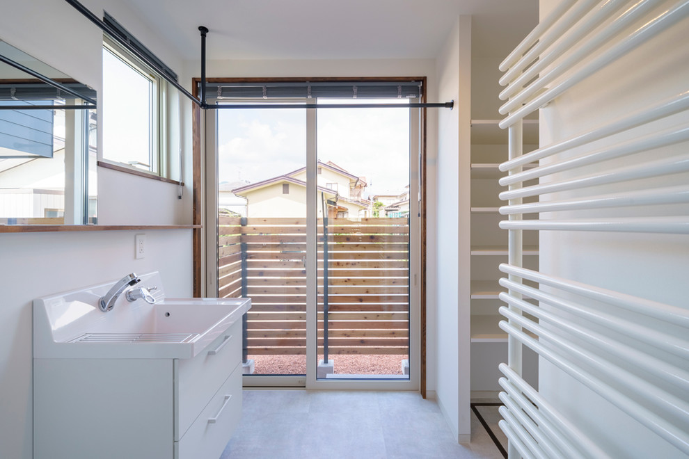 Idee per una sala lavanderia minimal di medie dimensioni con pareti bianche, lavasciuga e pavimento bianco