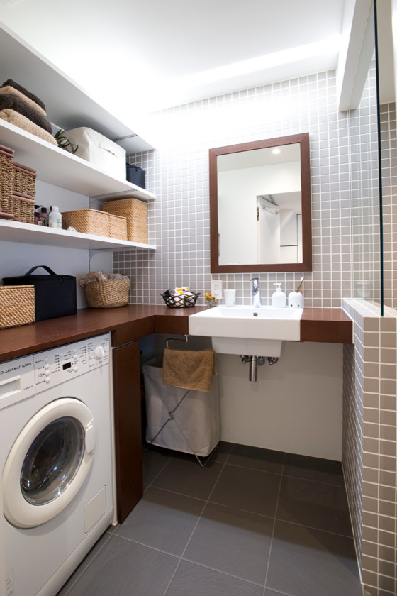 Photo of a medium sized modern l-shaped utility room in Tokyo with a single-bowl sink, open cabinets, white cabinets, wood worktops, white walls, slate flooring and a concealed washer and dryer.