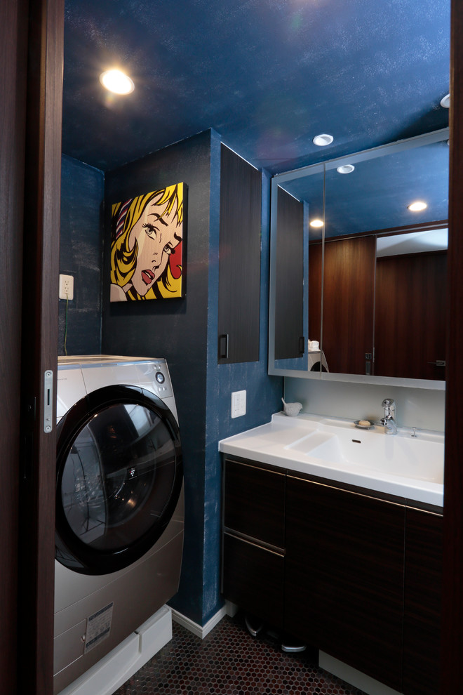 Cette photo montre une buanderie tendance avec un évier intégré, un placard à porte plane, des portes de placard marrons, un mur bleu et un lave-linge séchant.