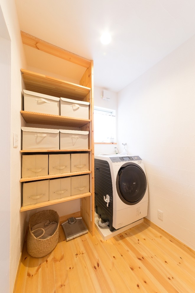 Bild på en lantlig tvättstuga med garderob, med öppna hyllor, vita väggar, mellanmörkt trägolv och brunt golv