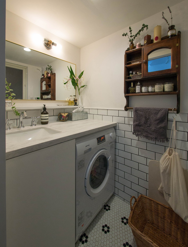 Exempel på en minimalistisk tvättstuga, med en undermonterad diskho och vita väggar