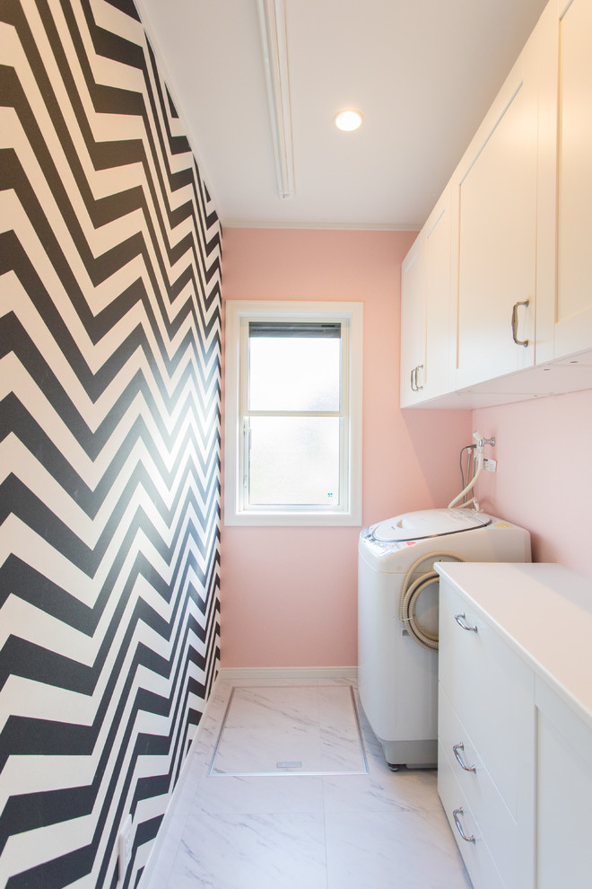 Design ideas for a small nautical utility room in Other with flat-panel cabinets, white cabinets, pink walls and grey floors.