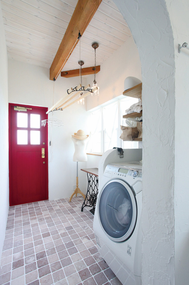 Foto på en medelhavsstil tvättstuga, med vita väggar och brunt golv
