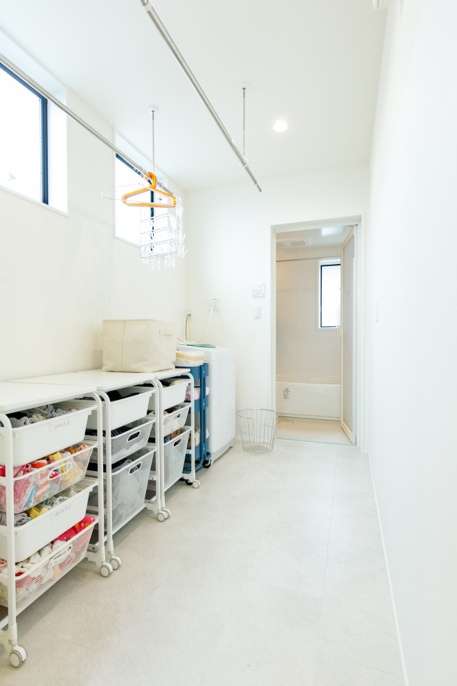 Minimalistisk inredning av en liten linjär tvättstuga enbart för tvätt, med vita väggar, vitt golv, öppna hyllor och vita skåp