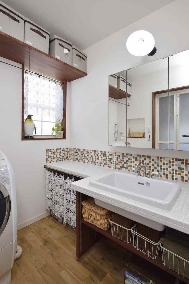 名古屋にある広い地中海スタイルのおしゃれな家事室 (I型、シングルシンク、オープンシェルフ、濃色木目調キャビネット、タイルカウンター、白い壁、淡色無垢フローリング) の写真