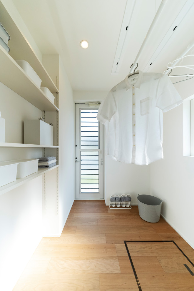 他の地域にあるモダンスタイルのおしゃれな洗濯室 (白い壁、無垢フローリング、茶色い床) の写真
