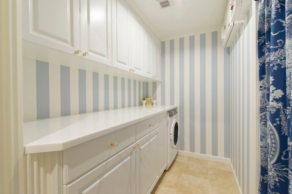 Idee per un ripostiglio-lavanderia chic di medie dimensioni con ante con bugna sagomata, ante bianche, pareti blu, pavimento con piastrelle in ceramica e lavasciuga