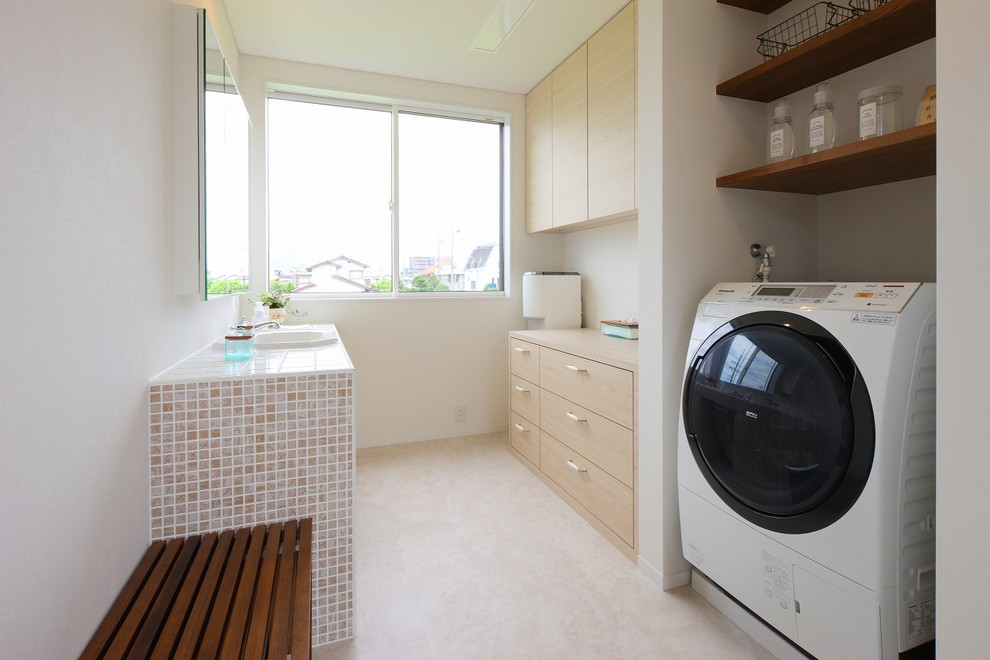 Diseño de lavadero minimalista con fregadero encastrado, armarios con paneles lisos, puertas de armario beige, paredes blancas y suelo beige