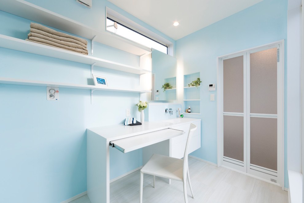 Immagine di una sala lavanderia moderna con pareti blu, pavimento beige e top bianco