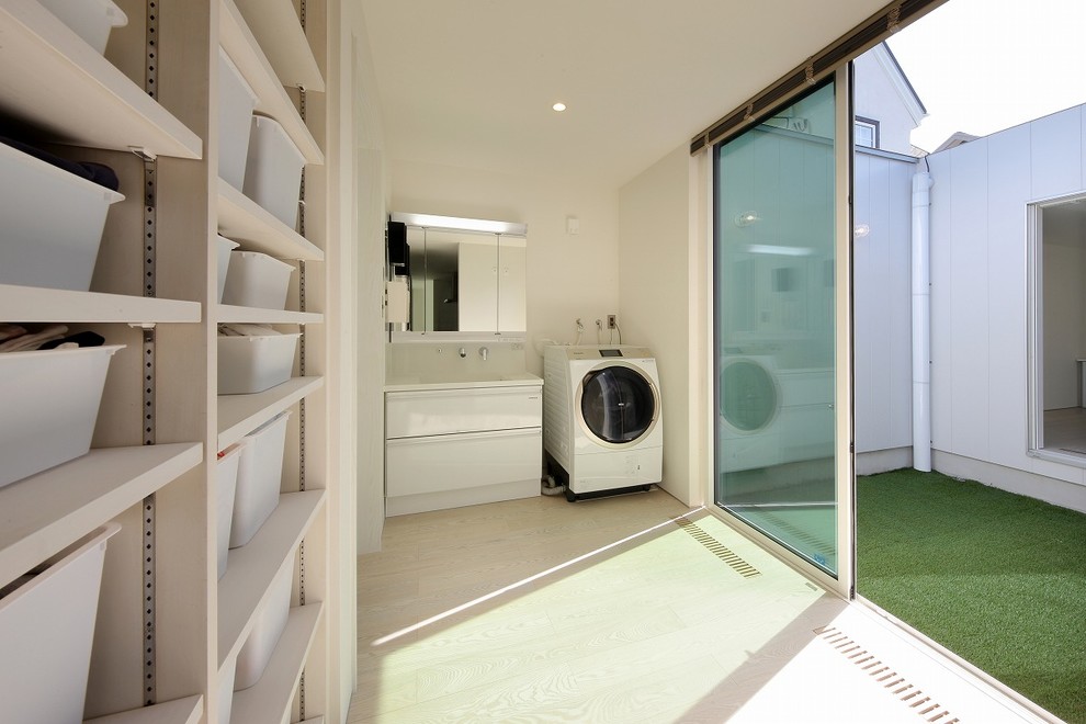Example of a minimalist laundry room design in Other with flat-panel cabinets and white cabinets