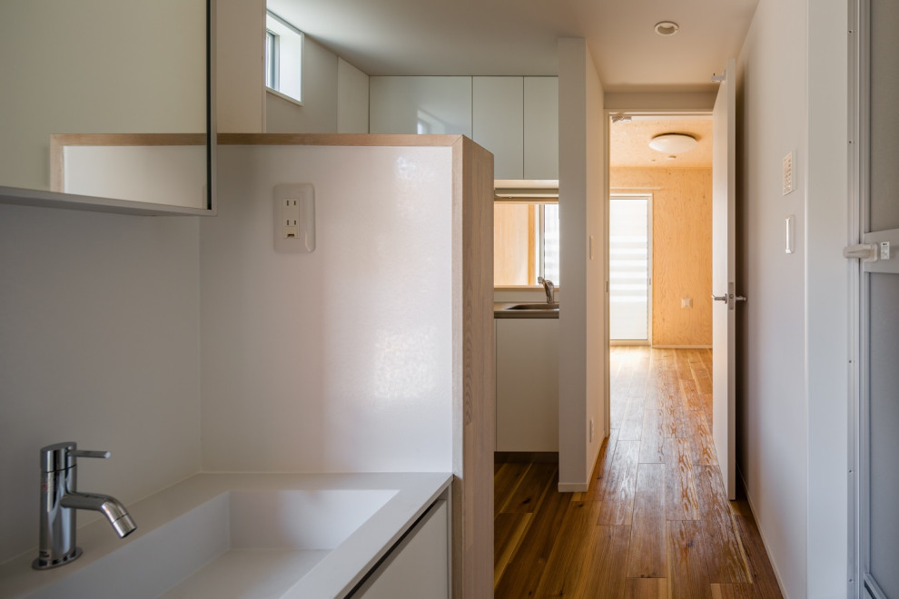 Utility room - mid-sized scandinavian u-shaped medium tone wood floor, beige floor, shiplap ceiling and shiplap wall utility room idea in Tokyo with an undermount sink, beaded inset cabinets, white cabinets, solid surface countertops, slate backsplash, white walls and white countertops
