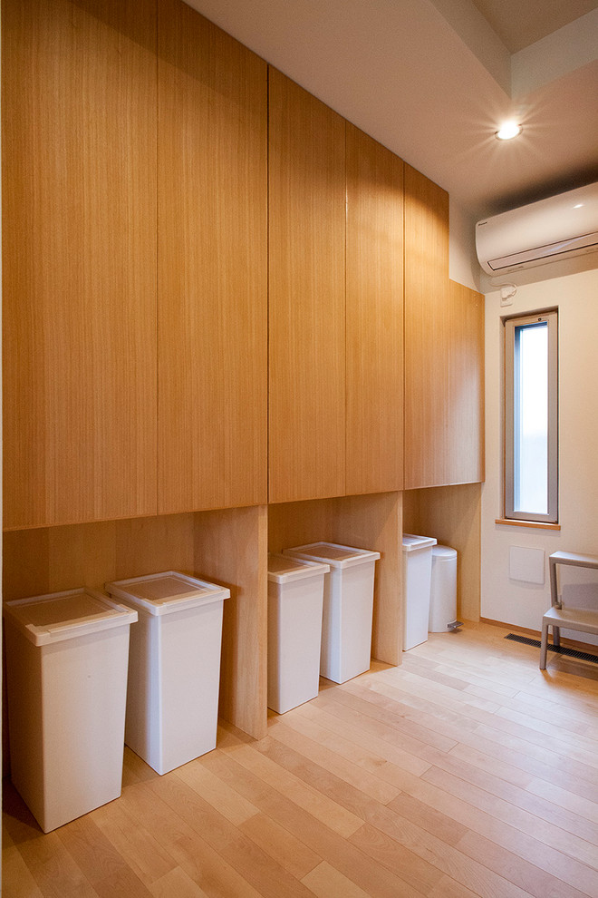 Cette image montre une buanderie rustique en bois brun multi-usage et de taille moyenne avec un placard à porte affleurante, un mur blanc, un sol en contreplaqué, un lave-linge séchant et un sol beige.