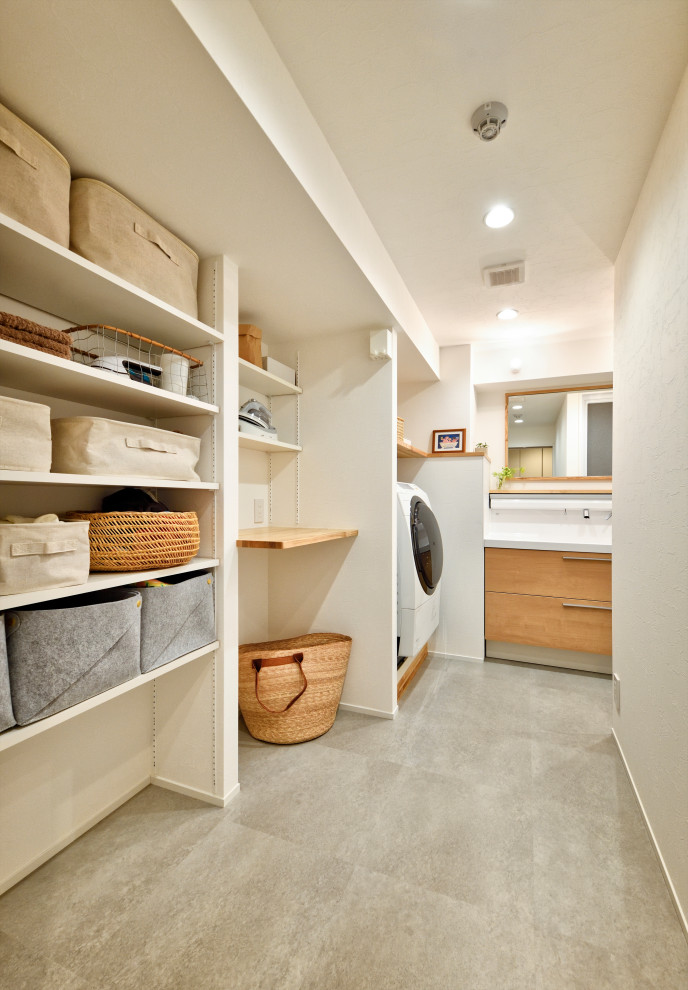 Multifunktionaler, Einzeiliger, Großer Moderner Hauswirtschaftsraum mit weißer Wandfarbe, Waschmaschine und Trockner integriert und grauem Boden in Tokio