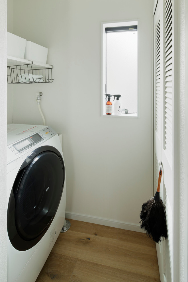 Diseño de cuarto de lavado moderno de tamaño medio con puertas de armario blancas, paredes blancas, suelo de madera en tonos medios y suelo beige