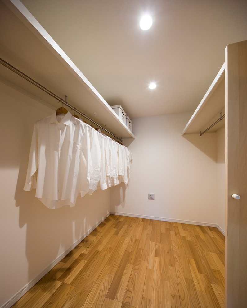 Ispirazione per un piccolo ripostiglio-lavanderia scandinavo con ante a filo, ante bianche, pareti bianche, pavimento in compensato e pavimento marrone