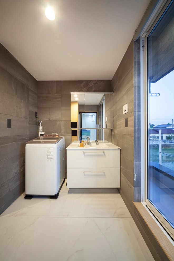 Immagine di una piccola lavanderia industriale con pavimento bianco, lavello integrato, ante lisce, ante bianche e pareti grigie