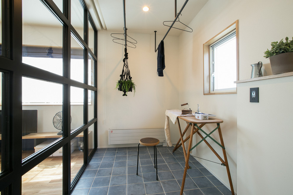 他の地域にある小さなインダストリアルスタイルのおしゃれな洗濯室 (白い壁、セラミックタイルの床、青い床) の写真