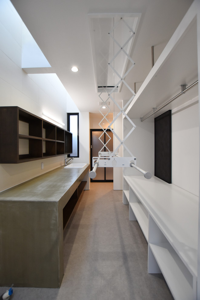 Cette image montre une buanderie minimaliste avec un placard sans porte, des portes de placard blanches, un sol en vinyl et un mur blanc.