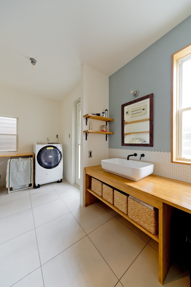 Immagine di una lavanderia multiuso industriale di medie dimensioni con lavello a vasca singola, nessun'anta, pareti blu, pavimento beige, top marrone e lavasciuga