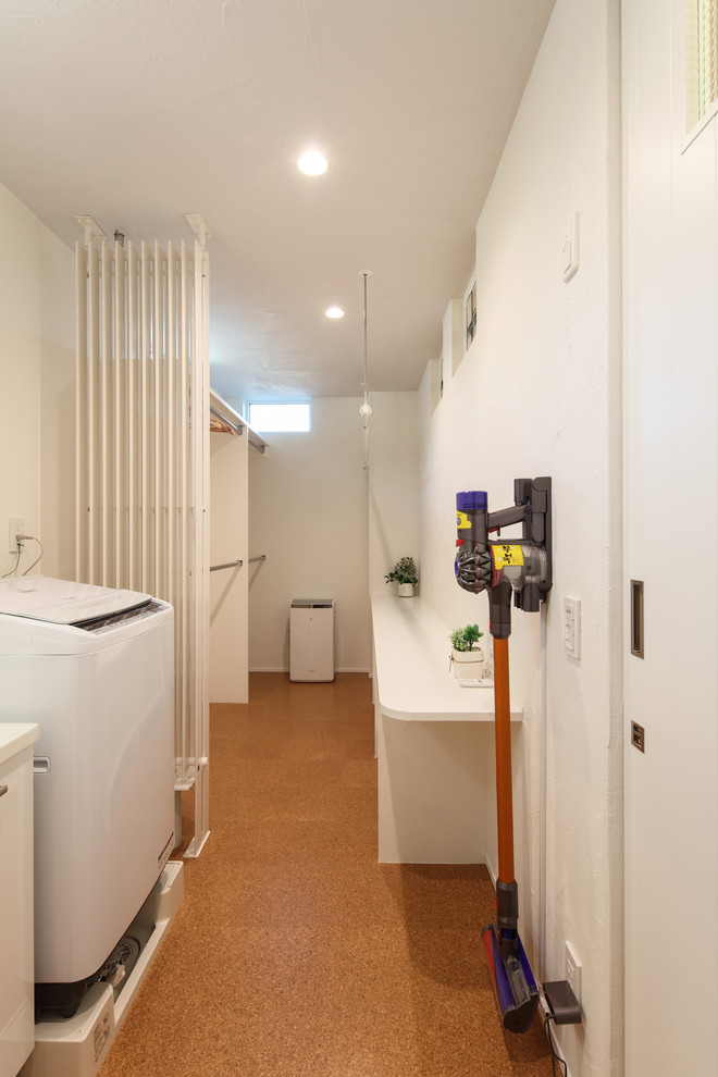 Immagine di una lavanderia moderna di medie dimensioni con pareti bianche, pavimento in sughero, pavimento arancione e top bianco