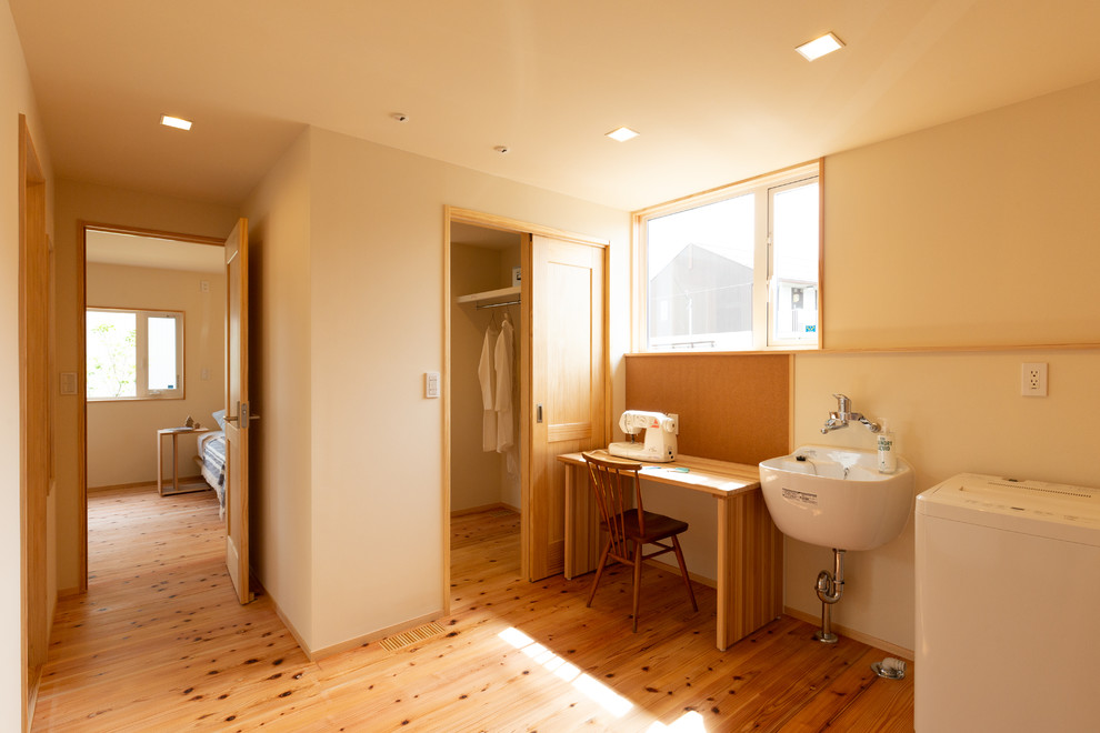 Multifunktionaler Landhausstil Hauswirtschaftsraum mit weißer Wandfarbe, hellem Holzboden und braunem Boden in Sonstige