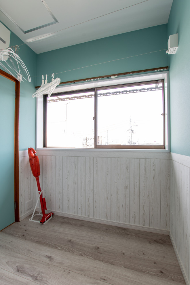 Inredning av en maritim liten tvättstuga enbart för tvätt, med blå väggar, plywoodgolv och beiget golv