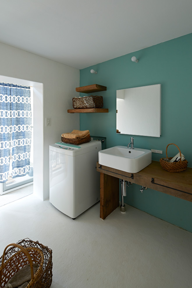 Réalisation d'une buanderie linéaire nordique avec un placard sans porte, un évier 1 bac, un plan de travail en bois, un mur vert, un sol blanc, un plan de travail marron et un lave-linge séchant.