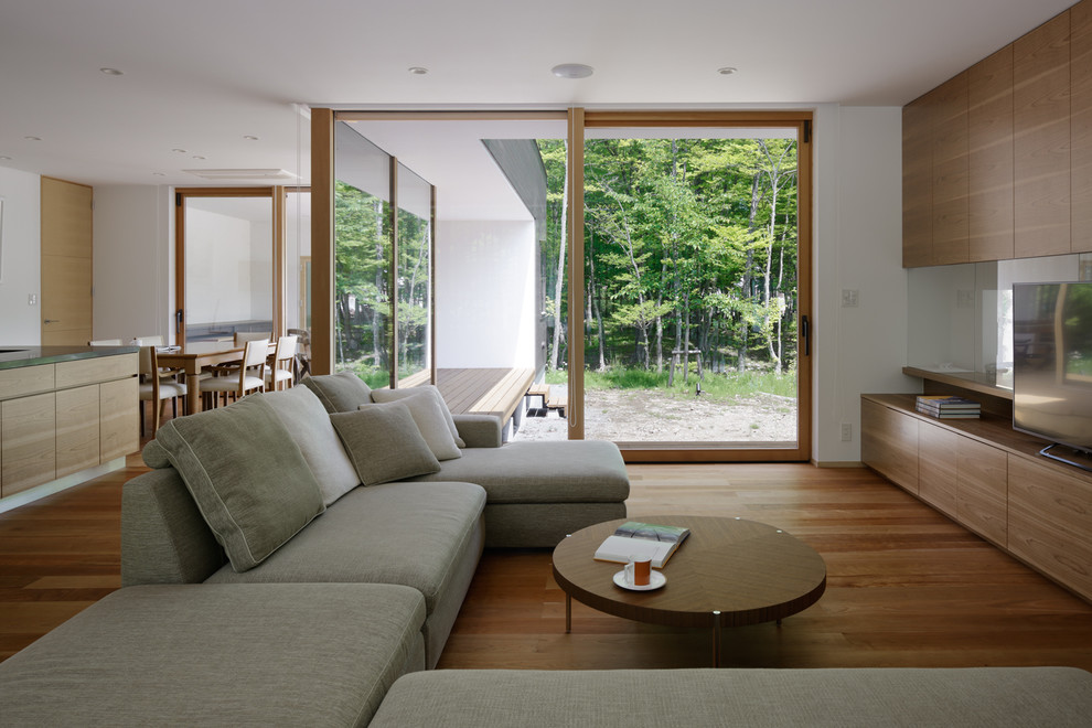 Свежая идея для дизайна: открытая гостиная комната в стиле модернизм с белыми стенами, паркетным полом среднего тона, отдельно стоящим телевизором и оранжевым полом - отличное фото интерьера