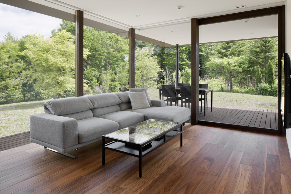 Foto di un soggiorno moderno aperto con pareti bianche, pavimento in legno massello medio, TV a parete e pavimento marrone