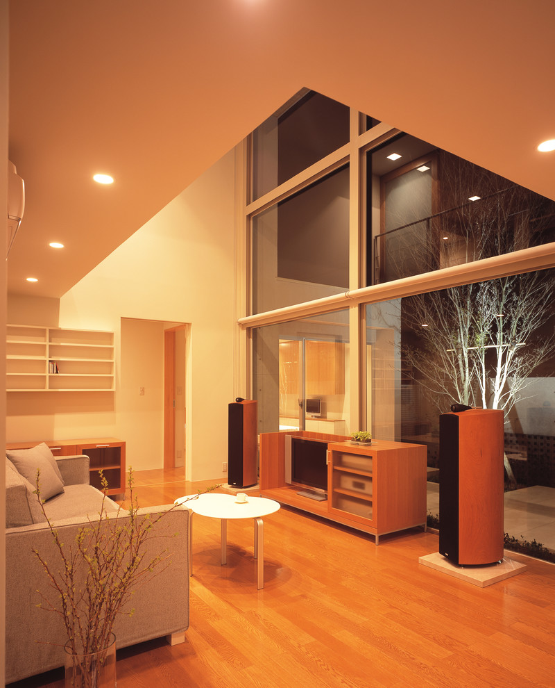 Foto på ett funkis vardagsrum, med beige väggar, mellanmörkt trägolv, en fristående TV och brunt golv