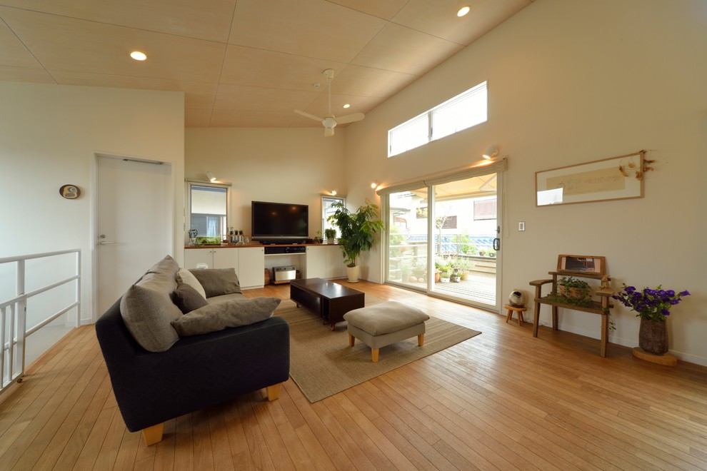 Photo of a contemporary living room in Other with white walls, medium hardwood flooring, a freestanding tv and brown floors.