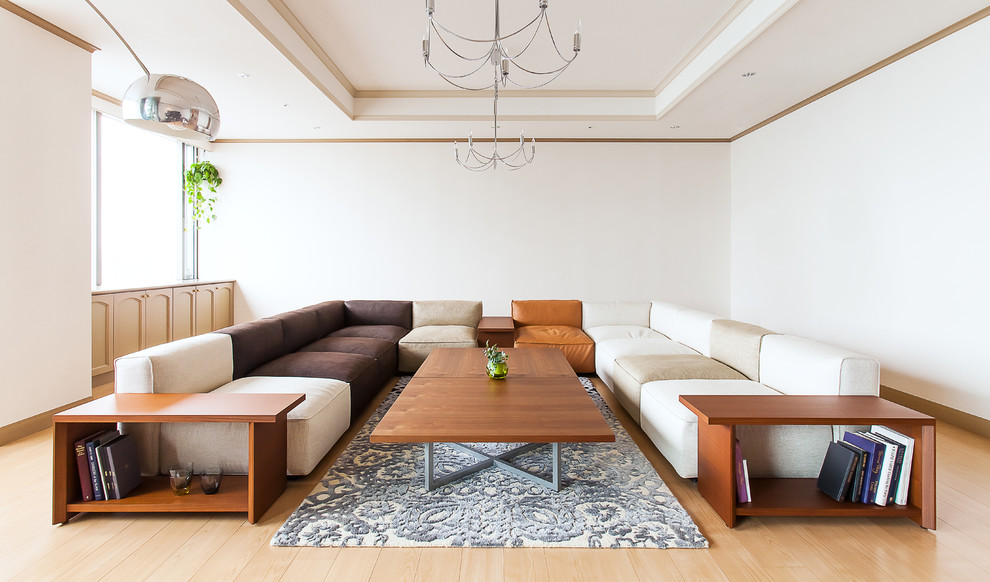 Ejemplo de salón minimalista sin chimenea y televisor con paredes blancas y suelo de madera clara