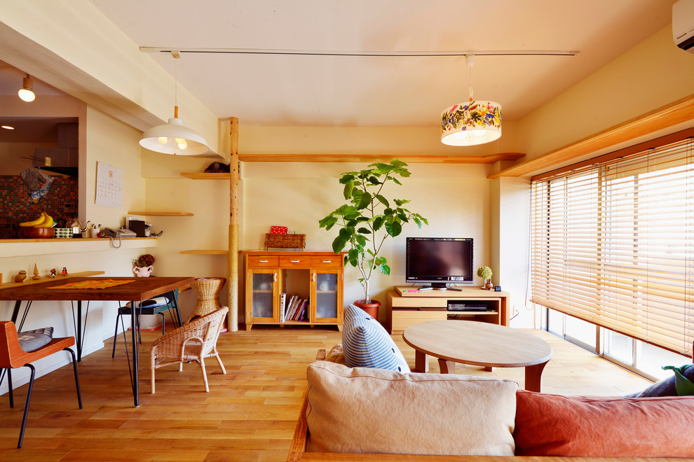 Modelo de salón abierto asiático con paredes blancas, suelo de madera en tonos medios, televisor independiente y suelo marrón