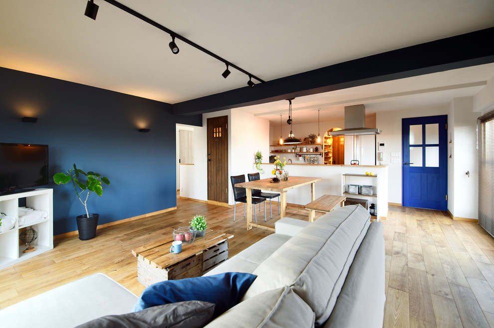 Skandinavisches Wohnzimmer mit blauer Wandfarbe, braunem Holzboden, freistehendem TV und braunem Boden in Tokio Peripherie