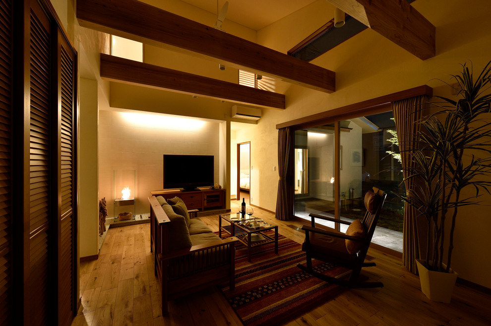 Modelo de salón abierto de tamaño medio con paredes blancas, suelo de madera en tonos medios y televisor independiente