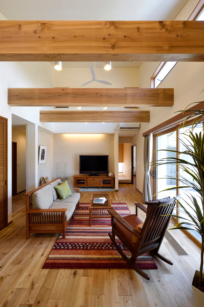 Imagen de salón abierto actual de tamaño medio con paredes blancas, suelo de madera en tonos medios, televisor independiente y suelo marrón