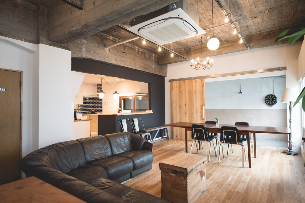 Industrial living room in Kobe with white walls, medium hardwood flooring and beige floors.