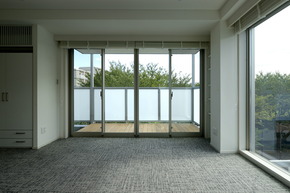 Modelo de salón abierto urbano grande sin chimenea con paredes blancas, moqueta, televisor colgado en la pared y suelo gris