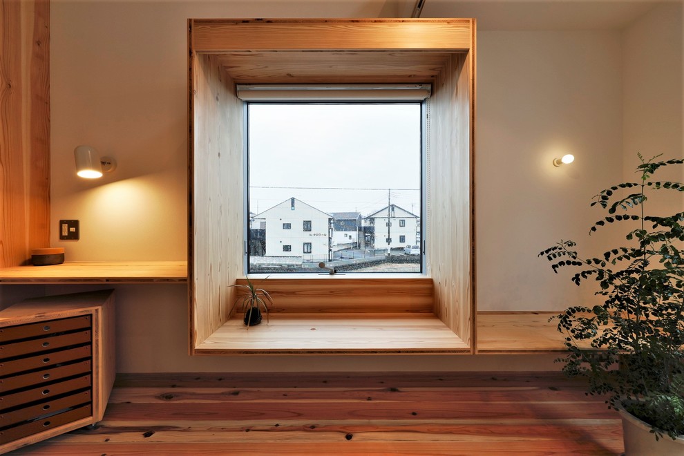 Asiatisk inredning av ett litet allrum med öppen planlösning, med vita väggar, mellanmörkt trägolv, en fristående TV och brunt golv