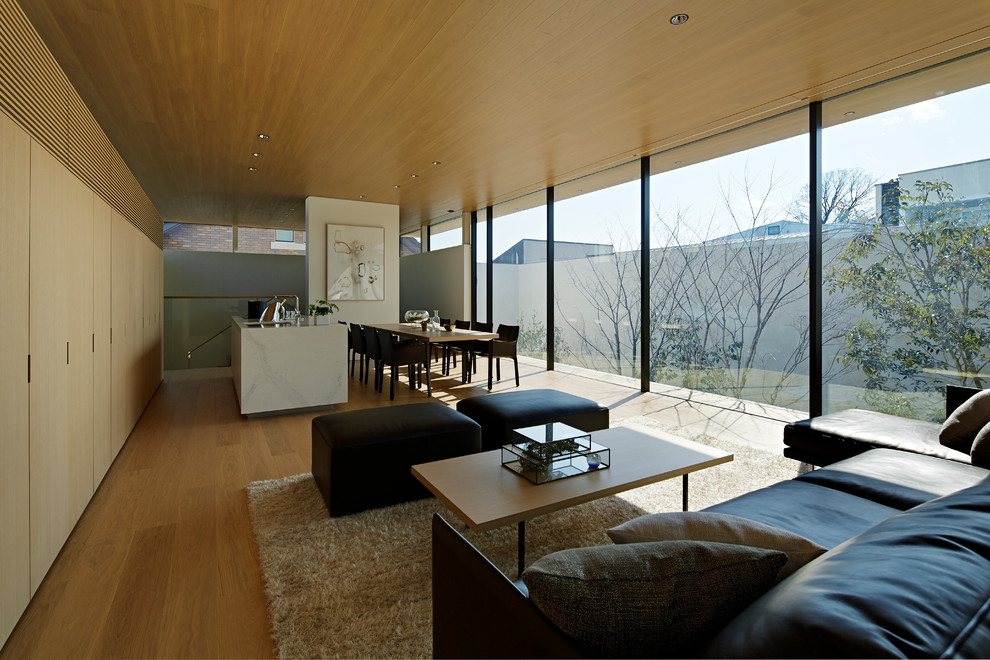 Immagine di un soggiorno moderno aperto con pareti bianche, pavimento in compensato, pavimento beige e TV nascosta